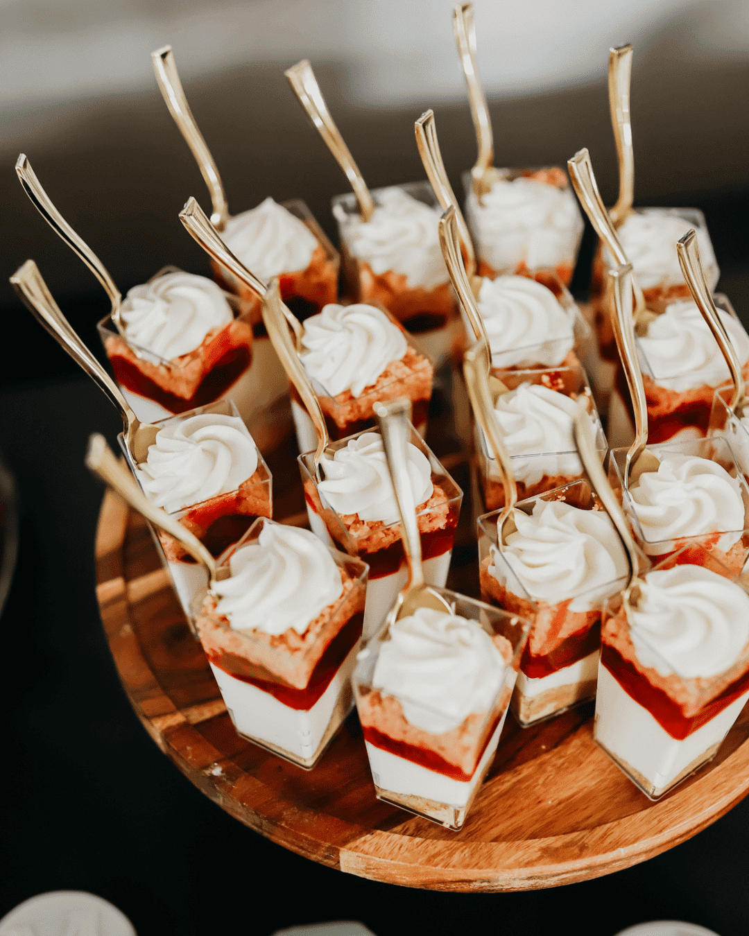 Mini dessert cups with layers of cream, cake, and strawberry, topped with swirls.
