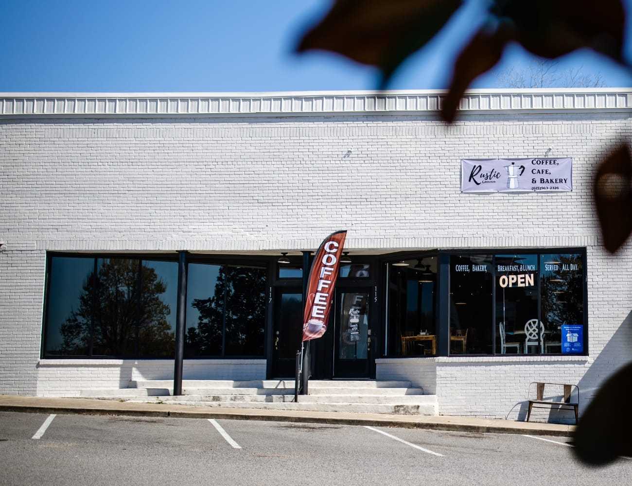 Exterior of a modern coffee shop with a "COFFEE" flag and an "OPEN" sign.