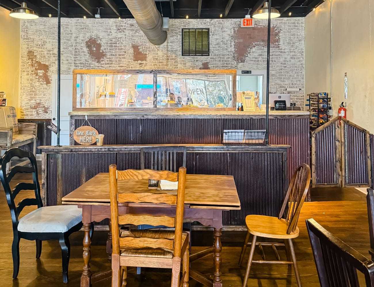 Cozy cafe interior with rustic wooden tables and chairs, open counter in the background.