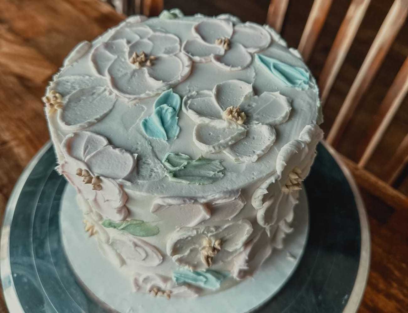 Decorative floral cake with pastel icing on a silver serving plate.